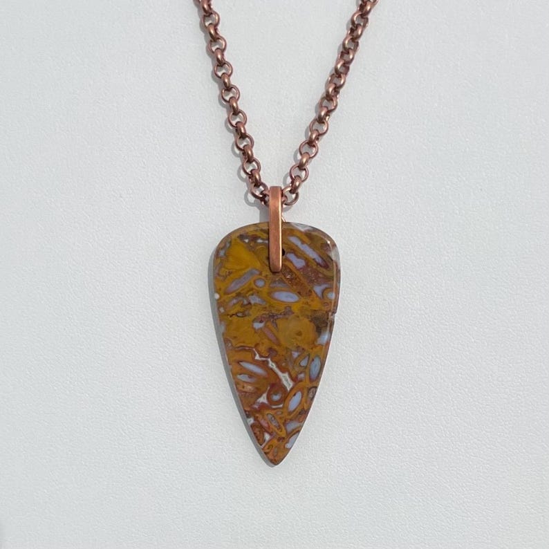 Op de afbeelding: Een koperen ketting met een hanger van bruin en wit agaat in de vorm van een traan.