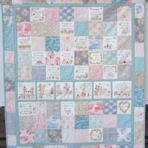 Może przedstawiać: Kołdra patchworkowa z różnymi wzorami kwiatowymi i ptasimi w odcieniach różowego, niebieskiego i zielonego. Kołdra składa się z kwadratów z różnymi wzorami i jest otoczona jasnoniebieskim obramowaniem.