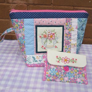 May include: A patchwork fabric zippered pouch with a floral design and a smaller matching pouch with a button closure. Both pouches feature embroidered floral designs.
