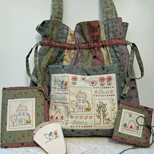 May include: A green, brown, and purple patchwork tote bag with a drawstring closure. The bag has a pocket on the front with embroidered images of houses, birds, flowers, and the words "Friends", "Home", and "Love". The bag comes with four smaller matching pouches with embroidered images of houses, birds, and bees.