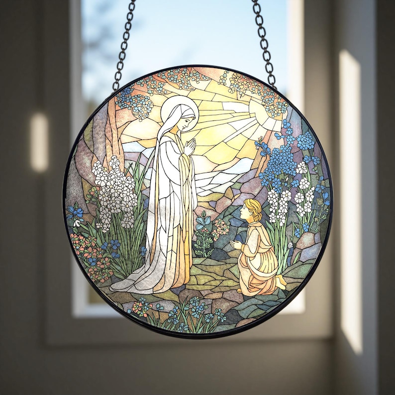 Peut inclure: Panneau de vitrail rond repr&eacute;sentant une sc&egrave;ne religieuse. Une femme en robe blanche se tient debout, les mains jointes, face &agrave; une personne agenouill&eacute;e. L'arri&egrave;re-plan pr&eacute;sente un soleil, des arbres et des fleurs dans des tons de bleu, jaune et vert. Le panneau est encadr&eacute; en noir et suspendu &agrave; une cha&icirc;ne.
