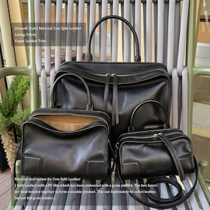 May include: A set of three black cow split leather bags, including a large tote with top handles, a medium satchel, and a small crossbody bag. The bags have silver zippers and are displayed on a chair.