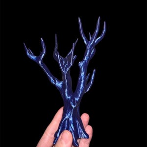 May include: A small, blue, 3D printed tree with a bare, branchy silhouette. The tree is made of a smooth, shiny plastic.