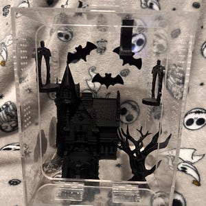 May include: A black 3D printed haunted house, a spooky tree, and bats are displayed inside a clear acrylic cube.