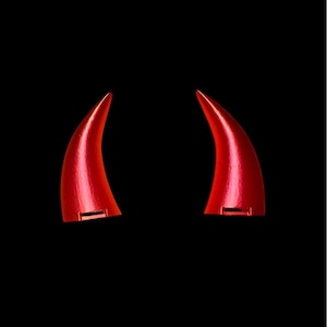 May include: A pair of red devil horns made of plastic. The horns are pointed and curved.