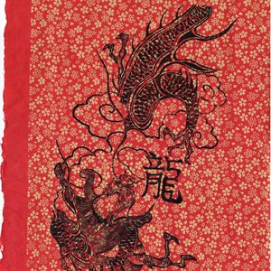 May include: A red paper with a black and white image of a dragon. The dragon is depicted in a traditional Chinese style with intricate details. The background is covered in a repeating pattern of small gold flowers.