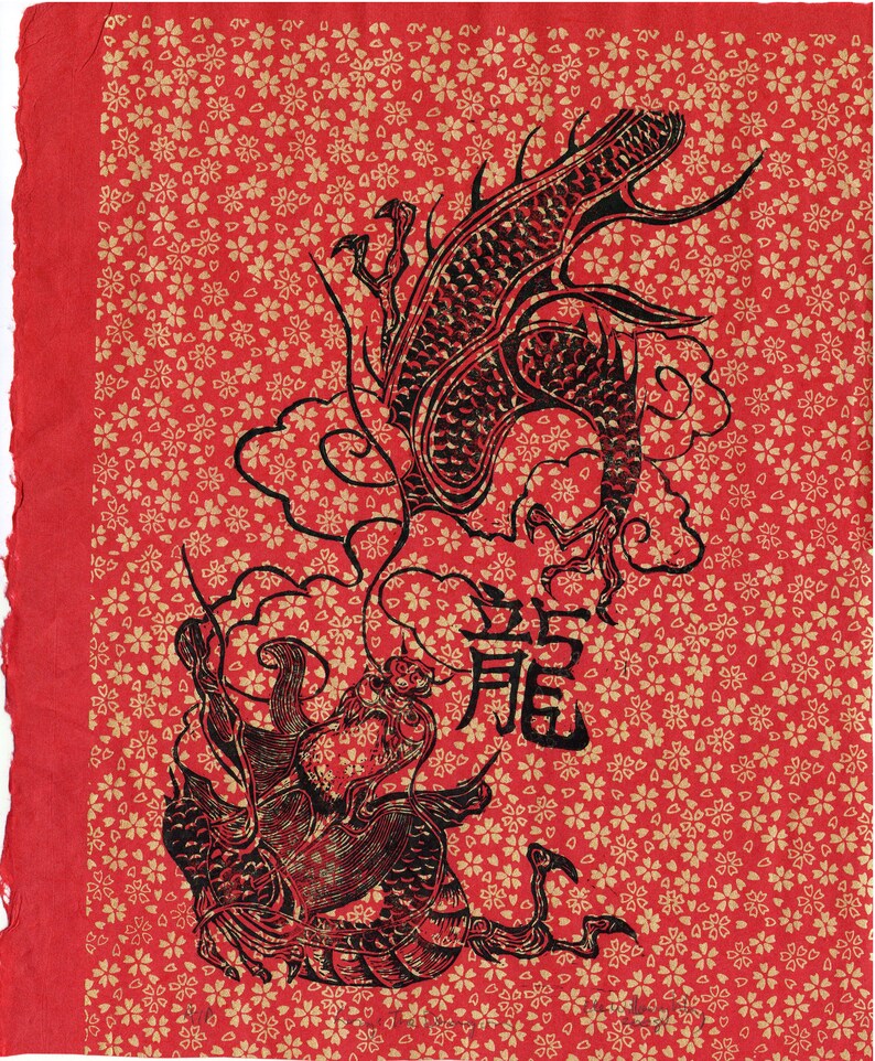 May include: A red paper with a black and white image of a dragon. The dragon is depicted in a traditional Chinese style with intricate details. The background is covered in a repeating pattern of small gold flowers.