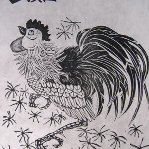 May include: Black and white woodcut print of a rooster with the Chinese character for "Rooster" in the top left corner. The rooster is standing on a background of stylized snowflakes. The print is titled "Gong-ji: The Rooster" and signed "Elle Willoughby 2003".