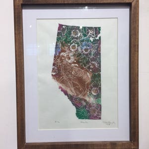 K&ouml;nnte beinhalten: Ein gerahmter Druck einer gr&uuml;nen, rosa und braunen Landschaft mit einer Silhouette eines Dickhornschafs. Der Druck ist mit "Alberta" betitelt und von "Elizabeth Willoughby 2019" signiert.