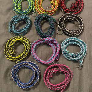 May include: Twelve braided cords with metal rings, each cord is a different color combination, including black, white, red, blue, green, yellow, and pink.