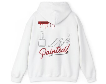 Op de afbeelding: Witte hoodie met een ontwerp op de achterkant met een nagellakfles, een hand met gelakte nagels en het woord "Painted!" in rood schrift. Het ontwerp bevat ook rode druppels en de woorden "Nail Shop".