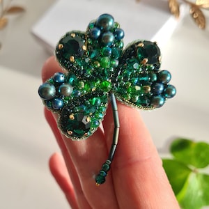 Broszka „Clover” w odcieniach szmaragdu i zieleni. Ręcznie robiona. Haftowana kryształami, kryształowymi koralikami, koralikami, cyrkoniami. Broszka talizman.