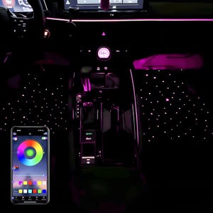May include: Interior car lighting system with pink ambient lights and a starry night effect on the floor. A smartphone displays a color wheel app for controlling the lights. The car's dashboard and console are visible.
