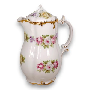 Puede incluir: Una cafetera de porcelana blanca con cuerpo festoneado y tapa a juego con remate. La superficie está decorada con motivos florales de rosas rosas, amarillas y moradas con hojas verdes, acentuada por un borde dorado en el borde y el asa.