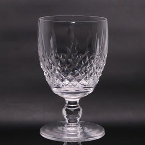 May include: A clear, cut crystal wine glass with a diamond pattern on the bowl. The glass has a stem and a round base. The glass is designed for serving wine. The glass is made of clear crystal.