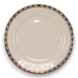 Peut inclure: Une assiette ovale blanche avec un bord noir et or. Le bord présente un motif répétitif de fleurs stylisées.
