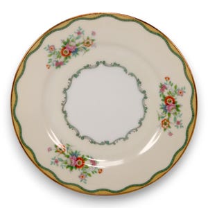 May include: A cream-coloured decorative plate with a scalloped edge and floral design. The plate has a yellow border with a green trim and gold accents. Small floral bouquets in pink, blue, and orange are arranged around the plate's edge.