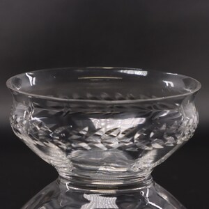 May include: A clear glass bowl with a cut glass design. The bowl is round and has a wide rim.