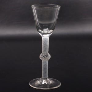 May include: A clear glass stemware piece featuring a flared bowl and a slender stem with an intricate white latticino mesh pattern. The stem includes a central decorative knop, and the entire structure rests on a circular, transparent glass base.