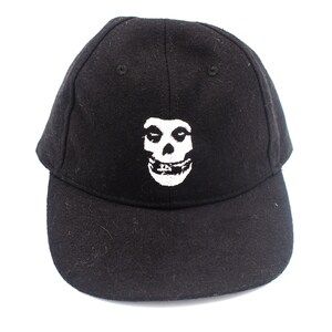 May include: Black baseball cap with a white skull and crossbones graphic. The skull has a surprised expression.