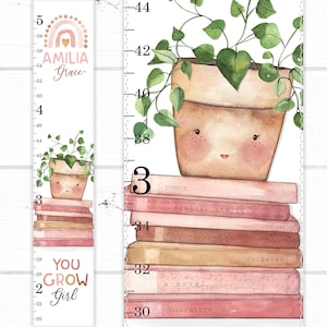 May include: A pink and white growth chart with a rainbow and the name "AMILIA Grace" at the top. The chart features a potted plant with a smiling face and a stack of books with titles like "poetry", "classic stories", and "a novel".