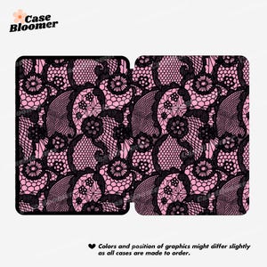 May include: A pink and black case with a lace pattern. The design features intricate black lace over a pink background. The text "Case Bloomer" is in the upper left corner. The text at the bottom says "Colors and position of graphics might differ slightly as all cases are made to order."