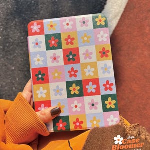 Puede incluir: Una funda para tablet blanca con un patr&oacute;n de cuadros coloridos con flores rojas, amarillas, verdes, azules y rosas. La funda tiene un logotipo "Shop Case Bloomer" con el texto "Personalized Cases".