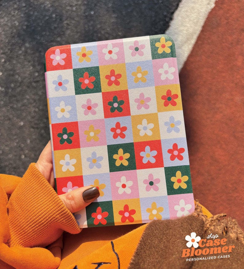 Puede incluir: Una funda para tablet blanca con un patr&oacute;n de cuadros coloridos con flores rojas, amarillas, verdes, azules y rosas. La funda tiene un logotipo "Shop Case Bloomer" con el texto "Personalized Cases".