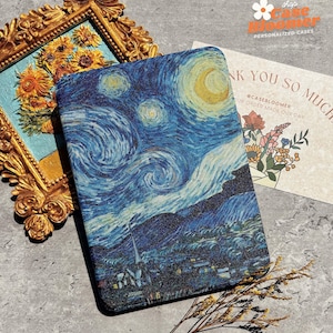 May include: A rectangular phone case with a print of Van Gogh's "Starry Night". The case is blue with swirling patterns, a crescent moon, and stars. It is next to a framed sunflower painting and a thank you card with floral illustrations.