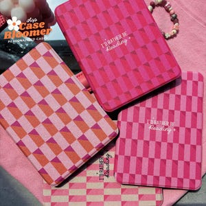 Puede incluir: Cuatro fundas para lector electr&oacute;nico Kindle a cuadros rosa y naranja con el texto "I'd rather be reading" impreso en ellas.