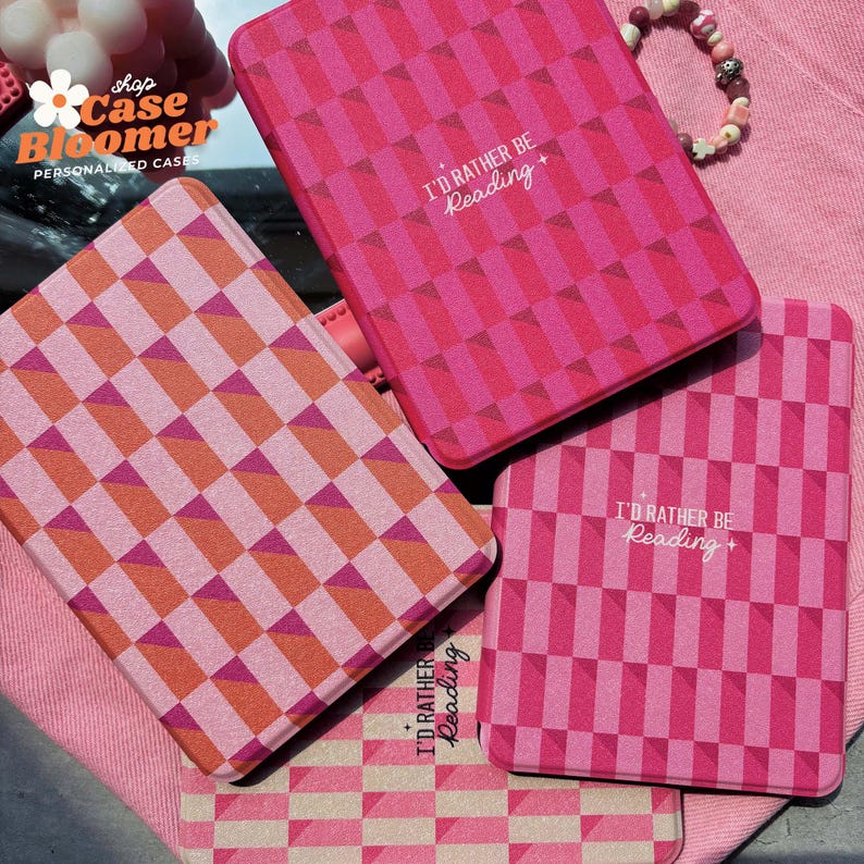 Puede incluir: Cuatro fundas para lector electr&oacute;nico Kindle a cuadros rosa y naranja con el texto "I'd rather be reading" impreso en ellas.