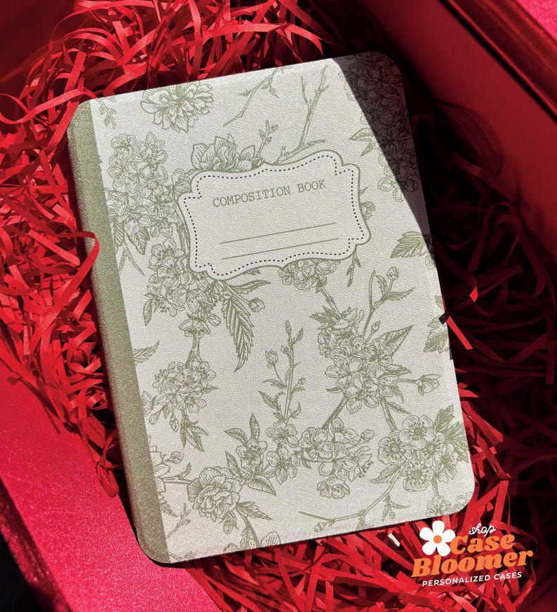 May include: A green composition book with a floral design and the text "COMPOSITION BOOK" on the front cover.