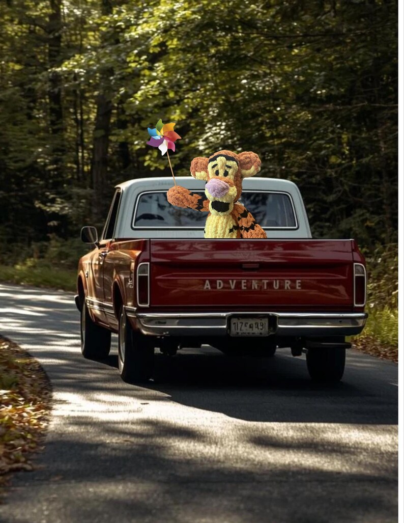 May include: A red vintage pickup truck with a white cab drives down a tree-lined road. A plush Tigger doll holds a colorful pinwheel in the truck bed. The word "ADVENTURE" is printed across the tailgate.