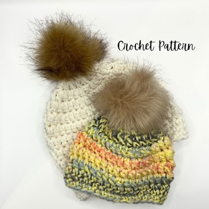May include: Two crocheted hats with faux fur pom poms. The smaller hat is a multi-colored yarn with stripes of yellow, orange, and blue. The larger hat is white with a brown faux fur pom pom. Crochet Pattern.