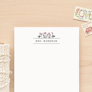 May include: A white stationery card with a floral design and the text "MRS. MARKHAM" in black.