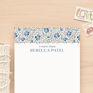 May include: A white notepad with a blue floral border at the top. The text "A note from Rebecca Patel" is printed in blue at the bottom of the notepad.