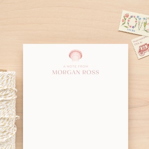May include: A white stationery notecard with a pink seashell illustration and the text "A note from Morgan Ross".