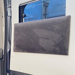Könnte beinhalten: Innenansicht einer Fahrzeugtür mit einem rechteckigen, dunkelgrauen, gepolsterten Paneel. Das Paneel ist auf einer weißen Oberfläche montiert, mit einem kleinen Fenster darüber. Der Text "Kissen nicht enthalten" ist unten sichtbar.