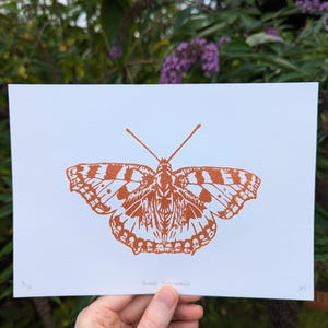 May include: A copper-coloured print of a Small Tortoiseshell butterfly on white paper. The print is numbered 5/10 and signed "RY".