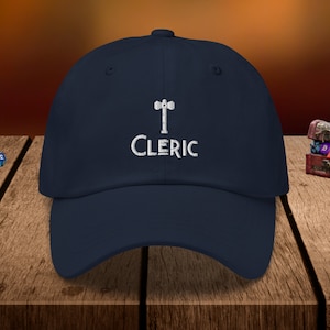 May include: A navy blue baseball cap with a white embroidered hammer and the word "CLERIC".