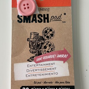 Puede incluir: Un bloc de notas de cartón marrón con un botón rosa adjunto. El bloc de notas tiene una ilustración en blanco y negro de un proyector de películas y el texto "SMASH pad" en negro. El texto "LOOK! REGARDE! IMIRA!" está en rojo. El texto "ENTERTAINMENT, DIVERTISSEMENT, ENTRETENIMIENTO" está en negro. El texto "list pad bloc-note bloc para listas" está en negro. El texto "30 pieces piéces piezas" está en negro.