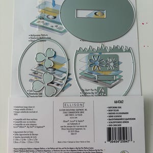 May include: A set of silver metal craft dies for a Sizzix machine, including an oval shape, a jagged-edged egg shape, and two flower-like shapes. The packaging displays the Ellison brand, the product number 664362, and dimensions of 2 7/8in x 3 3/4in.