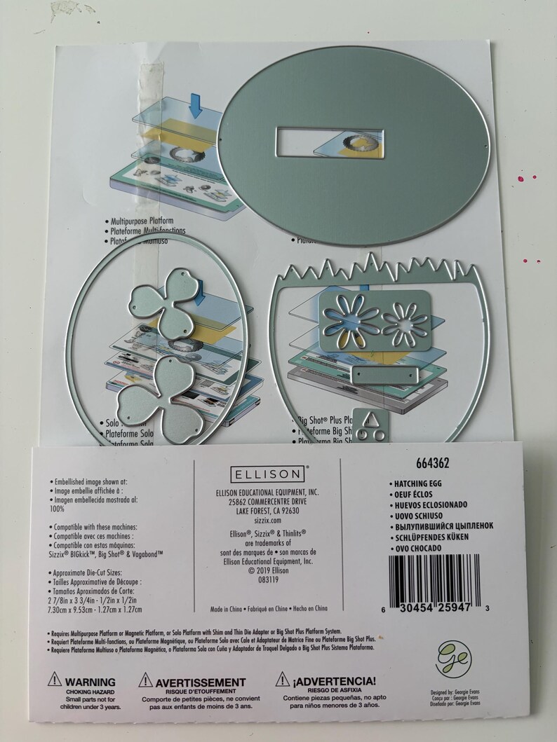 May include: A set of silver metal craft dies for a Sizzix machine, including an oval shape, a jagged-edged egg shape, and two flower-like shapes. The packaging displays the Ellison brand, the product number 664362, and dimensions of 2 7/8in x 3 3/4in.