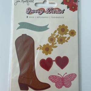 May include: A package of die cuts with a groovy theme. The package includes a brown cowboy boot, heart-shaped sunglasses, a butterfly, a banner, and flowers. The text "Groovy Darlin'" is displayed on the package.