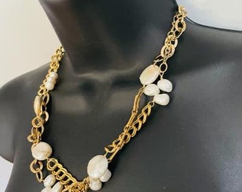 May include: A gold chain necklace with large white pearl accents. The necklace is layered with two different chain styles.