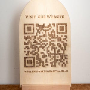 May include: A light-coloured wooden sign featuring a QR code and the text "VISIT OUR WEBSITE." The sign is supported by a small wooden base. The website address www.handmadesbymartyna.co.uk is printed at the bottom.
