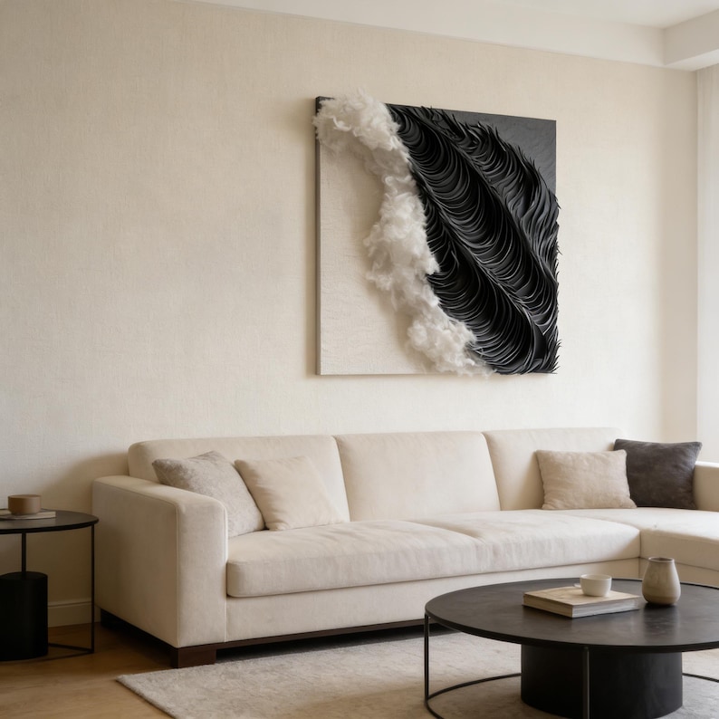 May include: Abstract wall art with a textured design in black and white. The artwork is mounted on a white background and hangs above a cream-coloured sectional sofa. A black coffee table and side table are in front of the sofa.