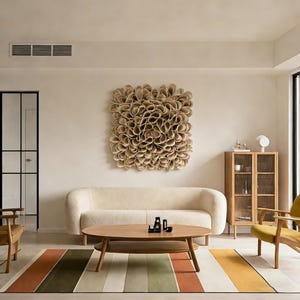 May include: A contemporary living room featuring a cream sofa, a wooden coffee table, and a striped rug. A large, textured wall art piece is mounted above the sofa. A wooden cabinet and armchairs complete the space.
