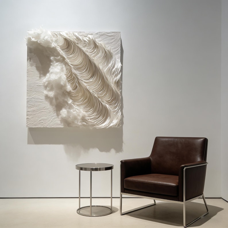 May include: A white, textured wall art piece with a wave-like design and fluffy cloud-like elements. A brown leather armchair with a silver frame and a small, round side table with a silver top are also in the room.