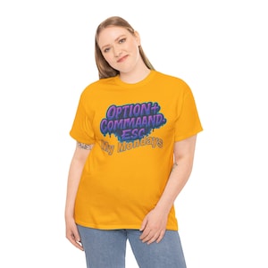 May include: Mustard yellow t-shirt with the text "OPTION+ COMMAND ESC My Mondays" in a blue and purple graffiti-style design. The shirt is a short-sleeved crew neck.